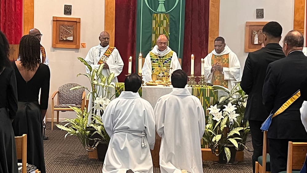 Archbishop Fabre celebrating mass at the altar with two altar servers kneeling.